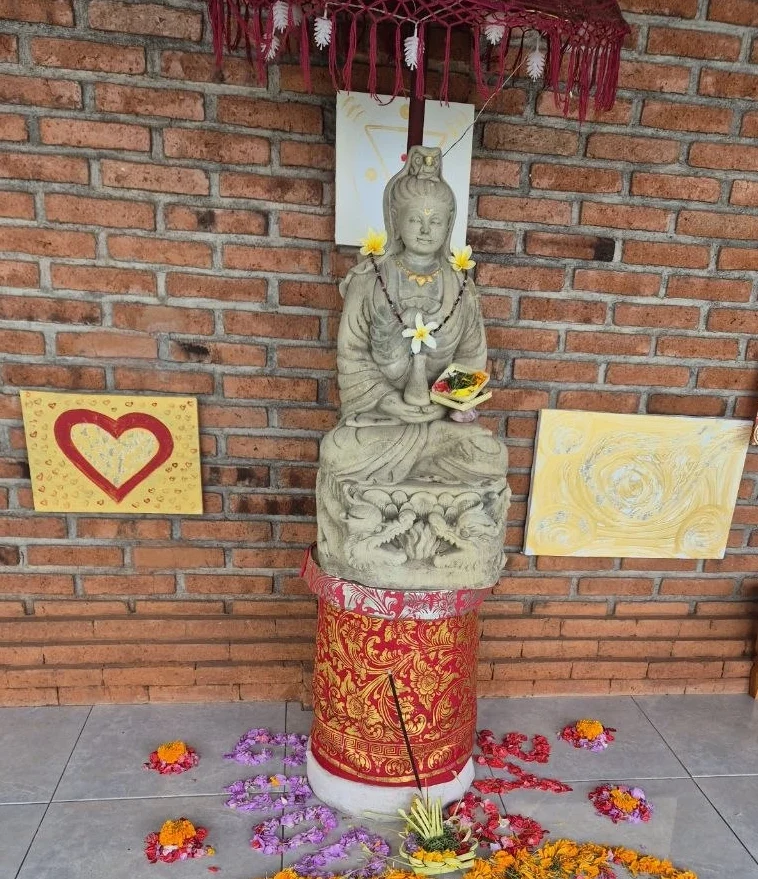 Eine Statue einer sitzenden-Figur, umgeben von Blumen und dekorativen Elementen.