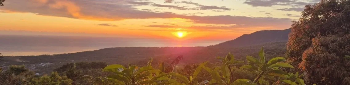 Sonnenuntergang über bewaldeten Hügeln mit weitem Blick ins Tal.