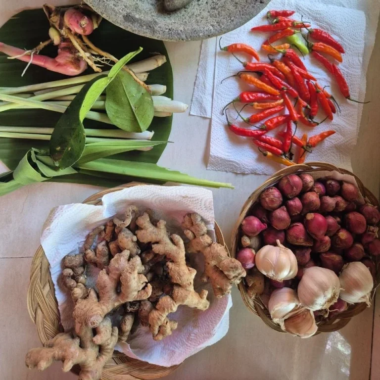 Eine Auswahl an frischen Gewürzen, einschließlich Ingwer, Chili und Knoblauch in Körben.