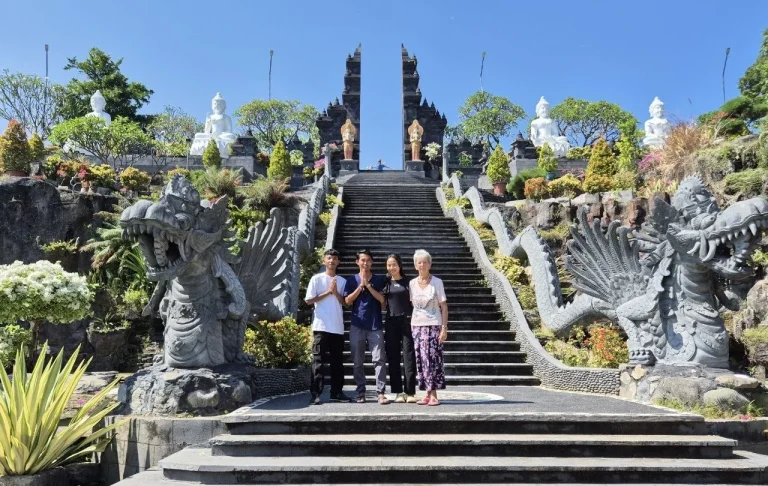 Fünf Personen stehen auf einer Treppe vor einem hinduistischen Tempel mit Skulpturen.