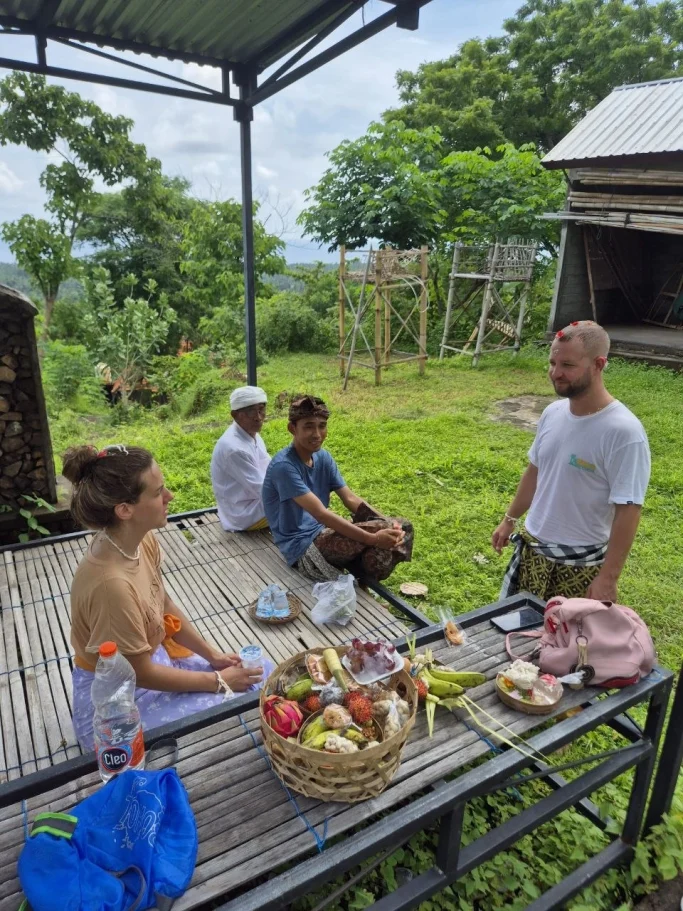Vier Personen sitzen auf einer Veranda, umgeben von Natur, während sie gemeinsam essen.