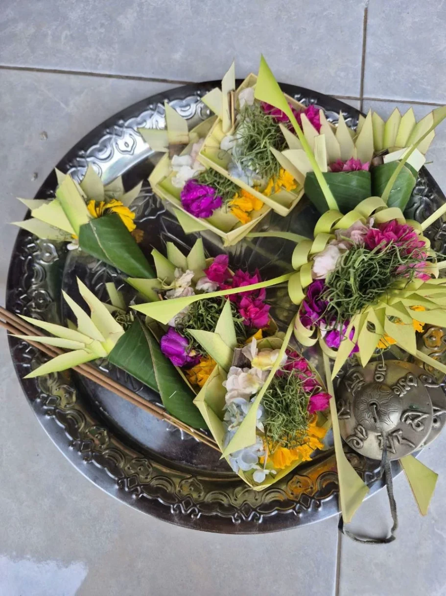 Traditionelle balinesische Opfergaben aus Blumen und Gräsern auf einem silbernen Teller.