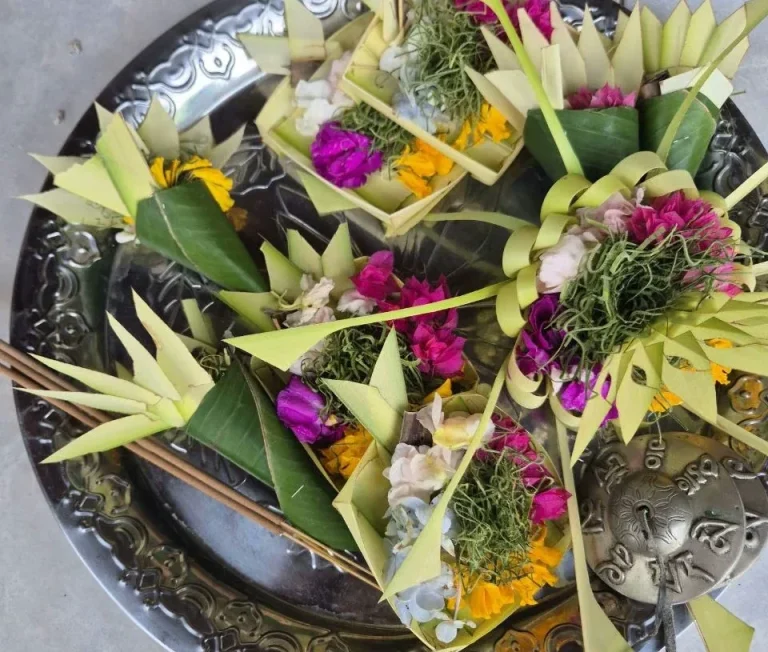 Traditionelle Opfergaben aus Palmblättern, Blumen und frischen Pflanzen auf einem Silbertablett.