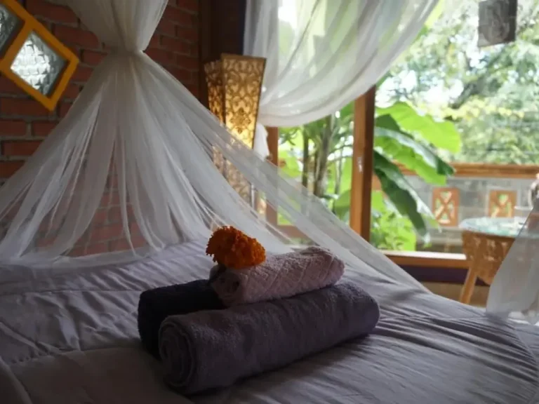Ein gemütliches Schlafzimmer mit Handtüchern auf einem Bett und Blick ins Grüne.