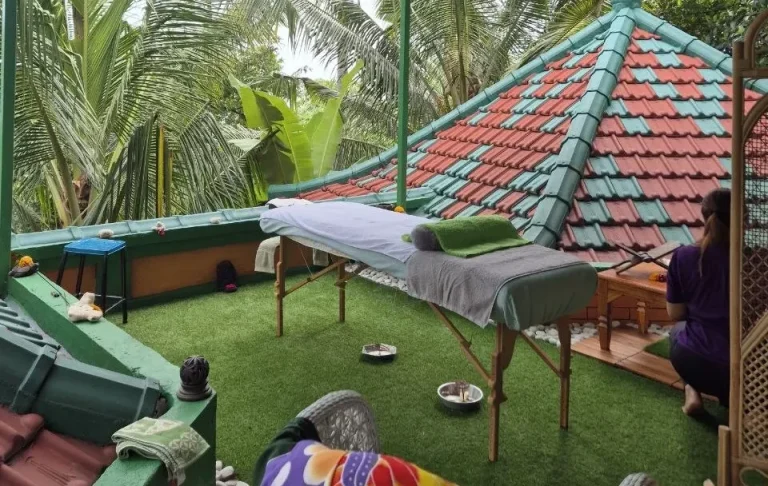 Entspannungsecke mit Massagetisch und tropischer Pflanzenumgebung auf einer Veranda.