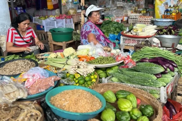 Bunter Markt mit frischem Obst, Gemüse und zwei Frauen, die die Waren verkaufen.