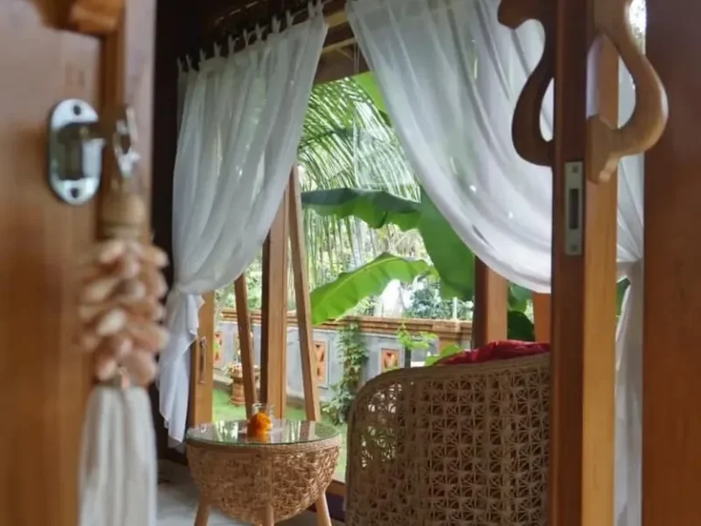 Heller Eingang mit weißen Vorhängen und Blick auf eine grüne Terrasse.