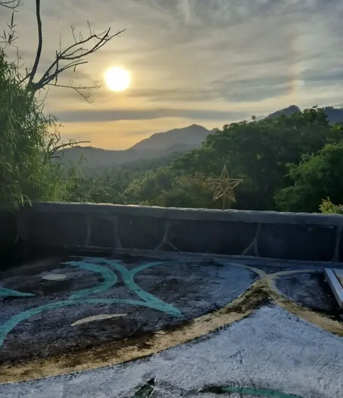 Sonnenuntergang über einer bewaldeten Berglandschaft mit Graffiti auf dem Boden.