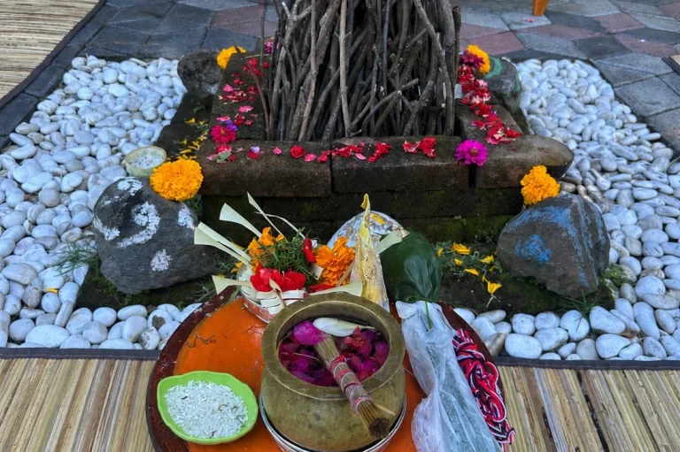 Feuerstelle mit Holz und Blumen, umgeben von zwei Personen in traditioneller Kleidung.