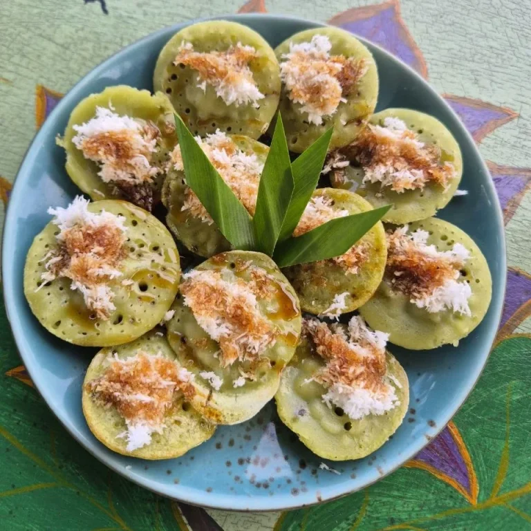 Traditionelles indonesisches Snackgericht auf einem blauen Teller, garniert mit Kokosraspeln.