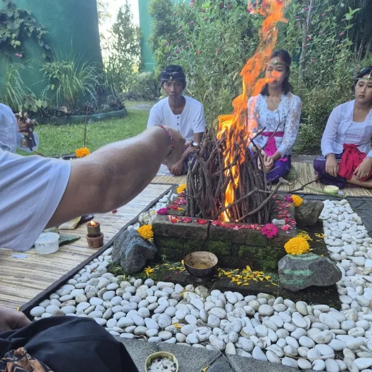 Holi Zeremonie mit brennendem Feuer, Teilnehmer in traditioneller Kleidung, Blumen dekoriert.