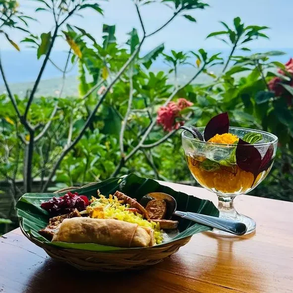 Ein Teller mit regionalen Speisen und ein Drink vor einer blühenden Landschaft.