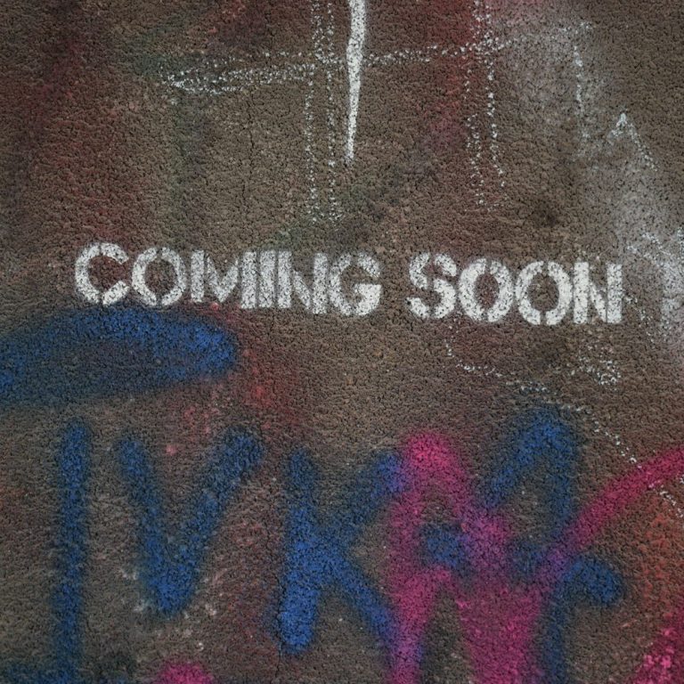 Graffiti mit dem Text "COMING SOON" auf einer grauen Wand.